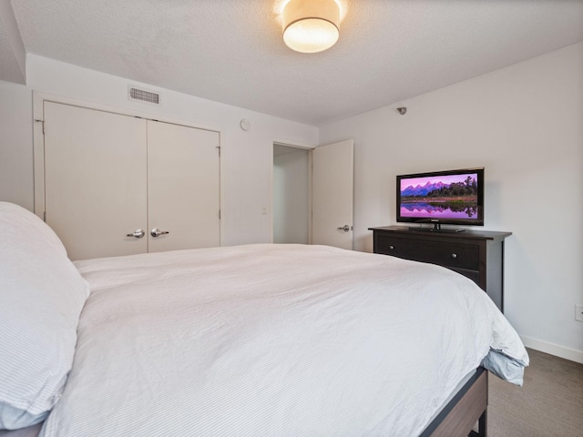 bedroom with baseboards, a textured ceiling, visible vents, and a closet