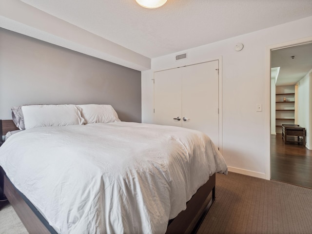 bedroom with dark colored carpet, a closet, visible vents, and baseboards