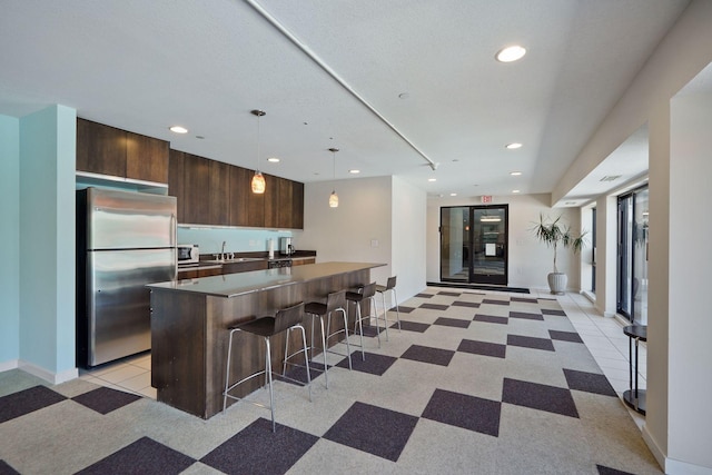 kitchen featuring a center island, a breakfast bar area, hanging light fixtures, freestanding refrigerator, and modern cabinets