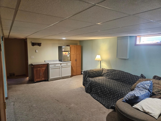 living area with carpet floors, visible vents, and a drop ceiling