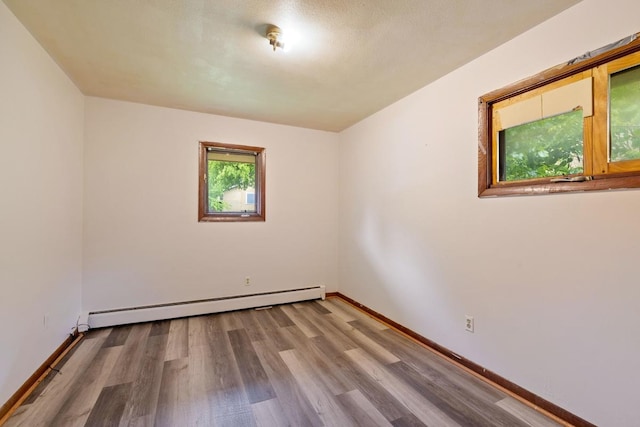 1022-1024 34th Ave N, Minneapolis, MN 55412 - empty room featuring a baseboard heating unit, wood finished floors, and baseboards