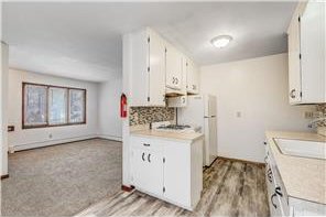 1022-1024 34th Ave N, Minneapolis, MN 55412 - kitchen with light countertops, decorative backsplash, a sink, white cabinets, and light wood-style flooring