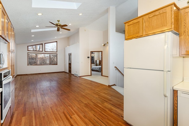 unfurnished living room featuring light wood-style flooring, vaulted ceiling with skylight, visible vents, and a textured ceiling