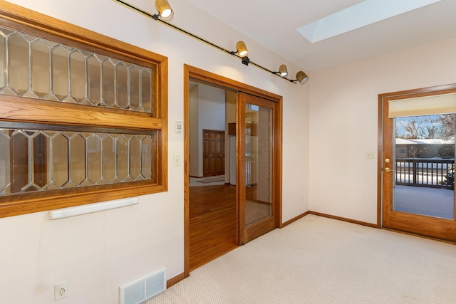 interior space featuring light carpet, a skylight, visible vents, and baseboards