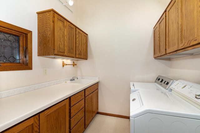 clothes washing area featuring separate washer and dryer, a sink, cabinet space, and baseboards