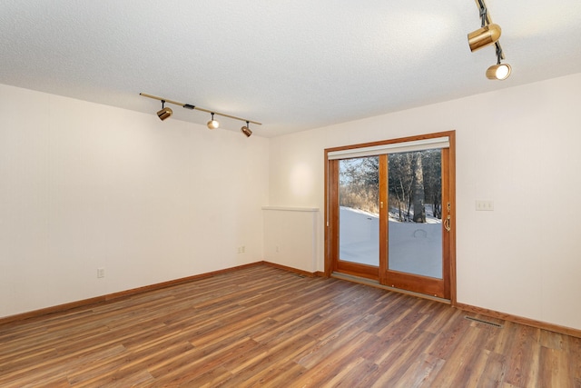 spare room with dark wood-style floors, a textured ceiling, and baseboards