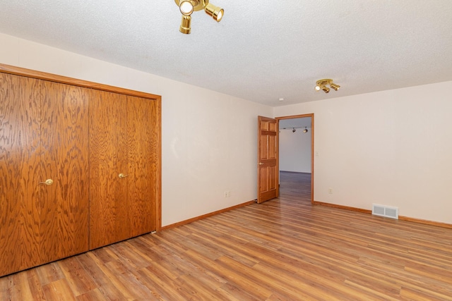 unfurnished bedroom featuring light wood-type flooring, baseboards, visible vents, and a textured ceiling