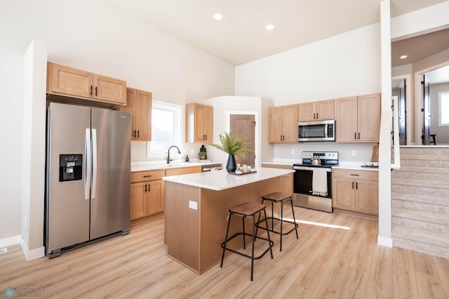 kitchen with a breakfast bar, light brown cabinets, a kitchen island, stainless steel appliances, and light countertops