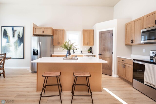 kitchen with a center island, light countertops, a kitchen breakfast bar, light wood-style floors, and stainless steel appliances