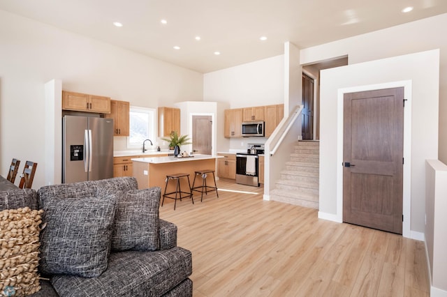 living area with baseboards, light wood finished floors, a high ceiling, recessed lighting, and stairs