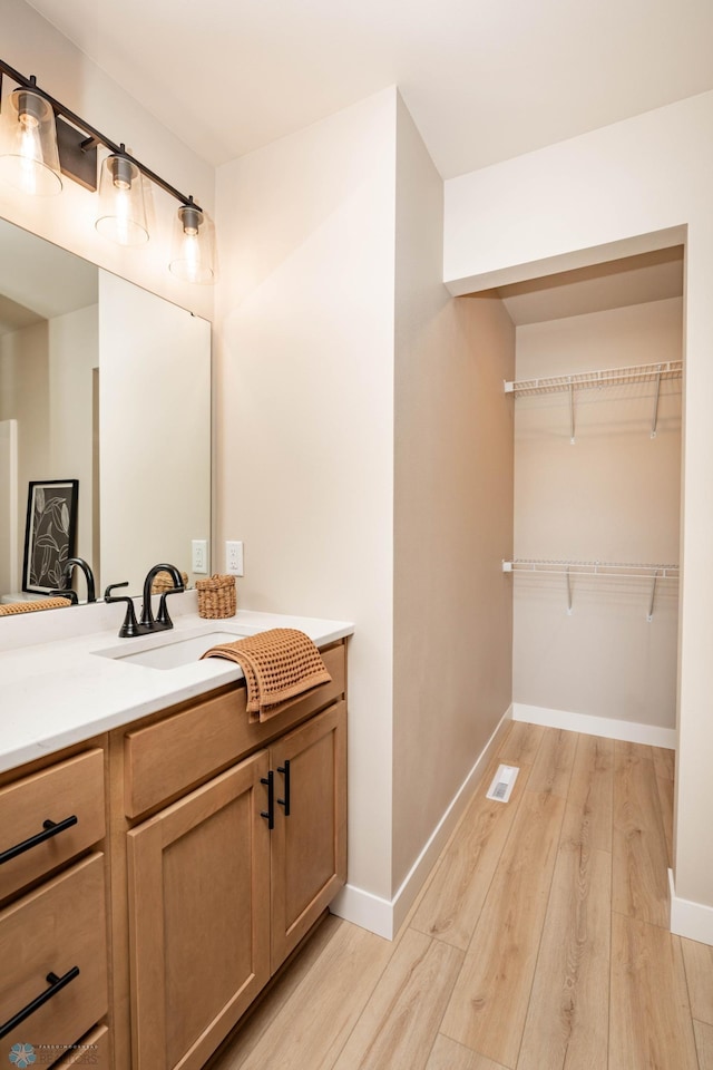 bathroom featuring visible vents, vanity, baseboards, and wood finished floors