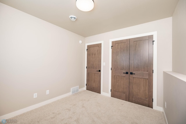 unfurnished bedroom with carpet, visible vents, a closet, and baseboards