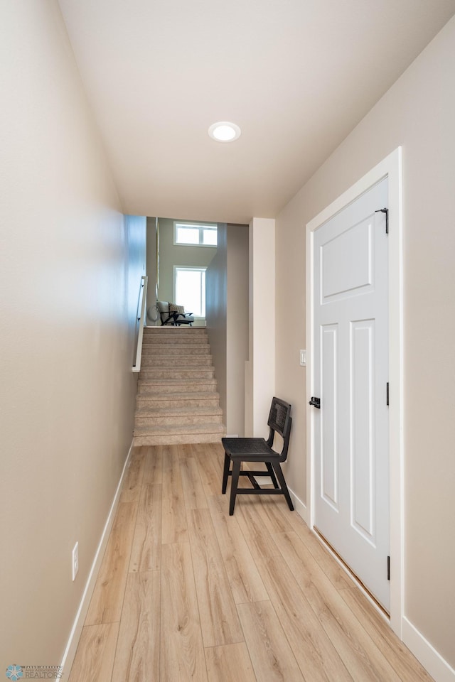 hall featuring light wood-type flooring, stairs, and baseboards