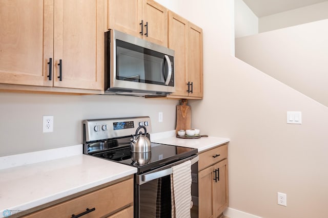 kitchen with light countertops, light brown cabinets, baseboards, and appliances with stainless steel finishes