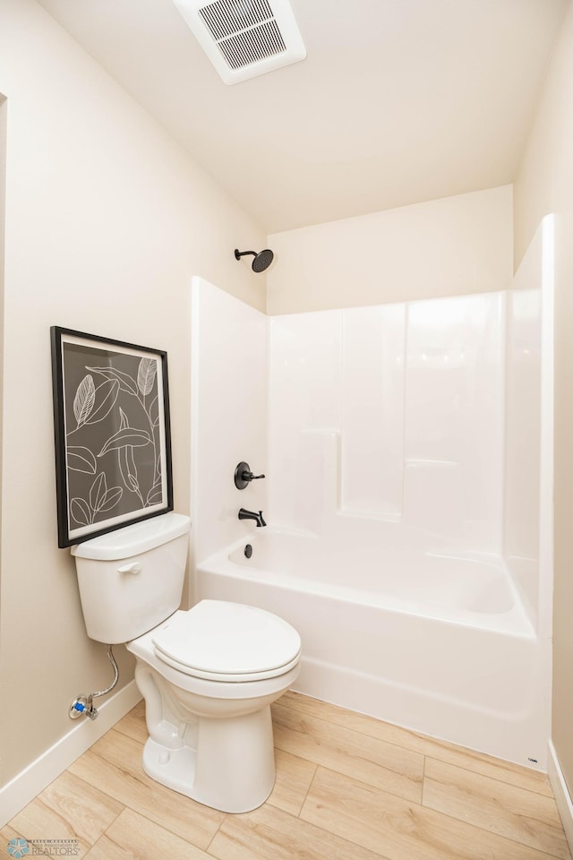 full bathroom featuring visible vents, toilet, wood finished floors, shower / washtub combination, and baseboards