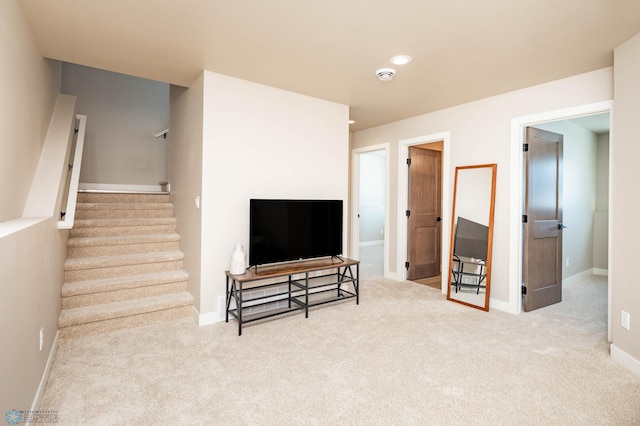 carpeted living area with stairs and baseboards