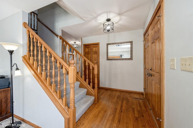 staircase featuring baseboards and wood finished floors