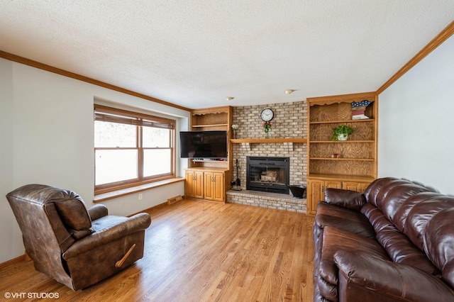 living room with a textured ceiling, light wood-type flooring, a fireplace, and crown molding