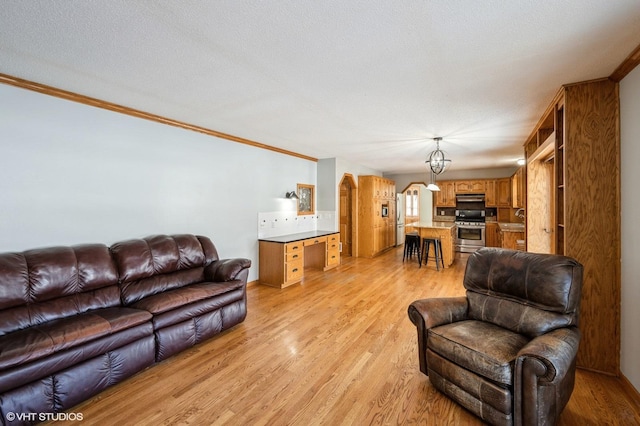 living area with a textured ceiling, ornamental molding, light wood-type flooring, and arched walkways