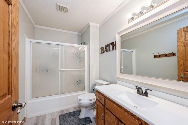 bathroom featuring visible vents, toilet, ornamental molding, combined bath / shower with glass door, and vanity