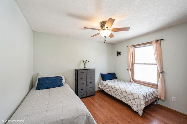 bedroom with a textured ceiling, a ceiling fan, and wood finished floors