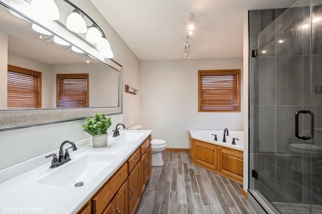 bathroom featuring a garden tub, a sink, toilet, and wood finished floors