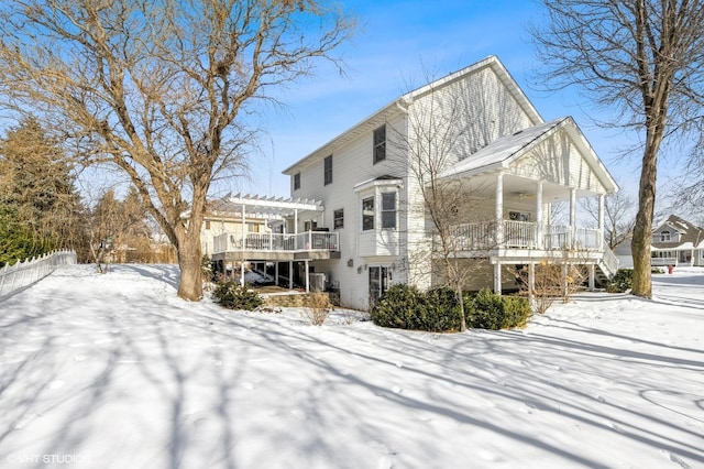 snow covered rear of property with a porch and a pergola