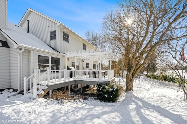 snow covered property with a deck, a chimney, fence, and a pergola