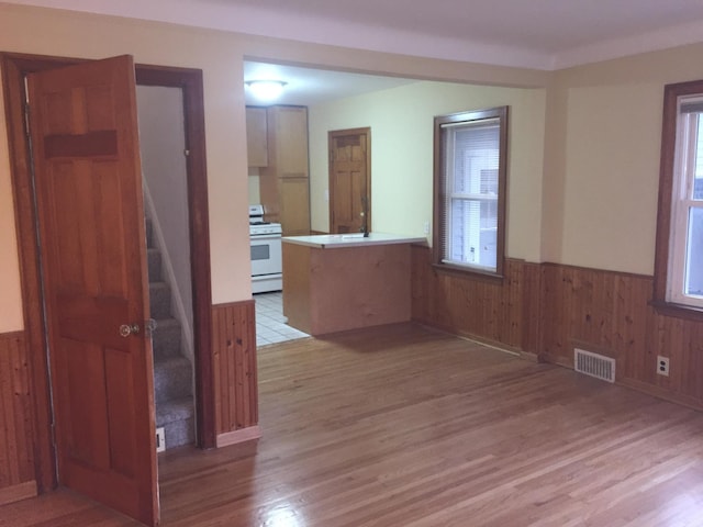 632 Morgan Ave S, Minneapolis, MN 55405 - empty room featuring wainscoting, light wood finished floors, stairs, and wooden walls