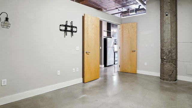 unfurnished room with finished concrete flooring and baseboards