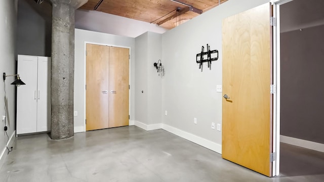 unfurnished bedroom featuring concrete floors, baseboards, and a closet