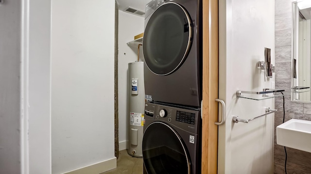 laundry room featuring electric water heater, laundry area, a sink, visible vents, and stacked washing maching and dryer