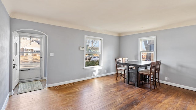 dining room with dark wood-style floors, a wealth of natural light, and baseboards