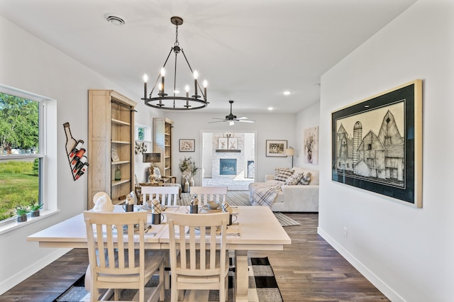 dining room with dark wood-style flooring, a glass covered fireplace, visible vents, and baseboards