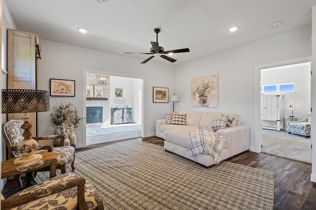 living room featuring dark wood-type flooring, a glass covered fireplace, baseboards, and recessed lighting