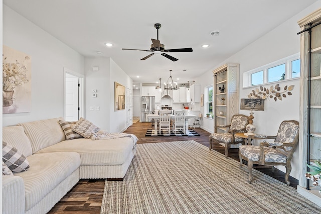 living area featuring dark wood-style floors, ceiling fan with notable chandelier, and recessed lighting