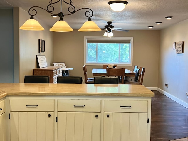 kitchen with a textured ceiling, baseboards, light countertops, dark wood finished floors, and pendant lighting