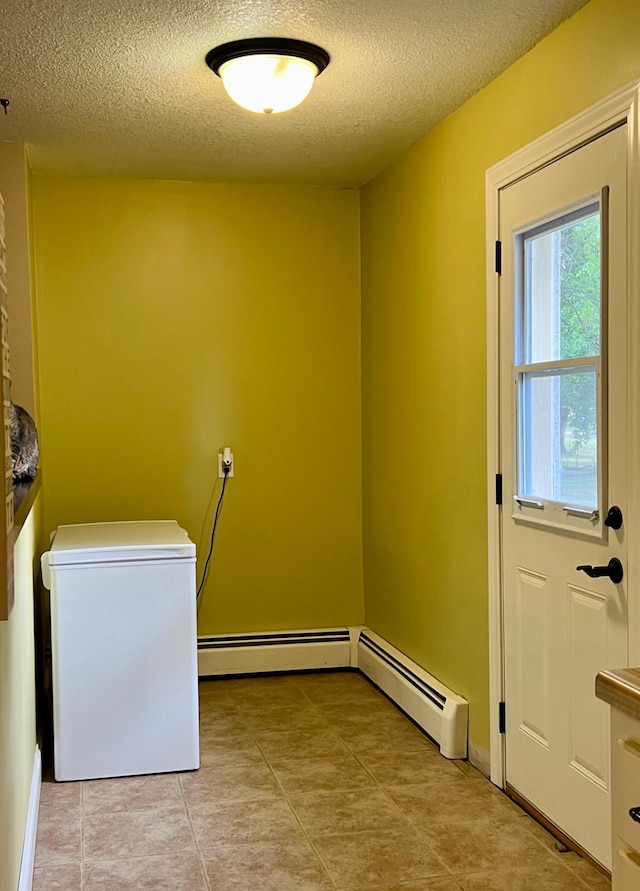 clothes washing area featuring laundry area, a baseboard heating unit, a textured ceiling, and light tile patterned flooring