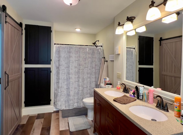 full bath with double vanity, a sink, toilet, and wood finished floors