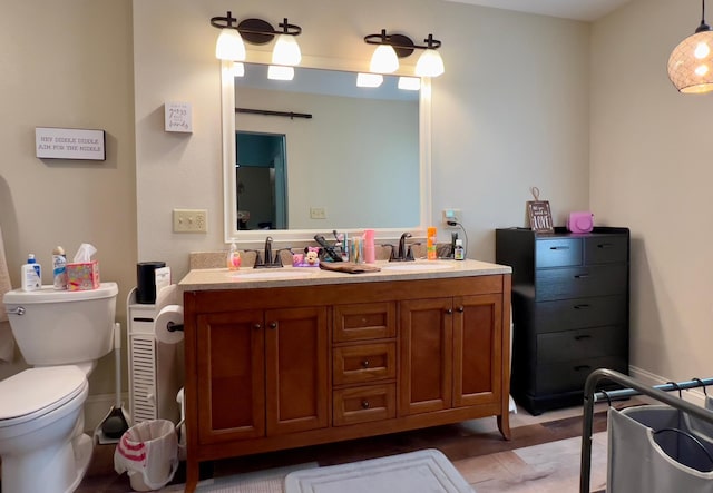 bathroom featuring double vanity, a sink, toilet, and baseboards