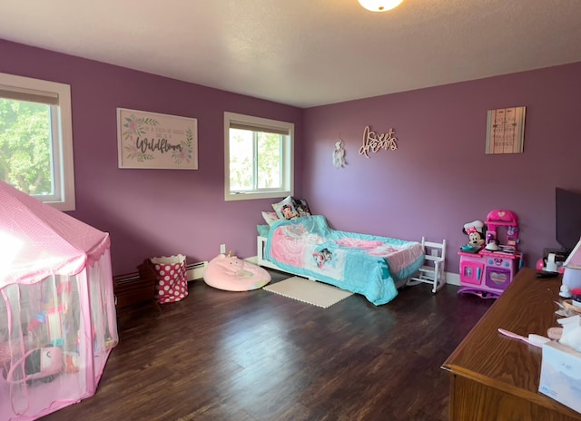 bedroom with dark wood-type flooring and baseboard heating