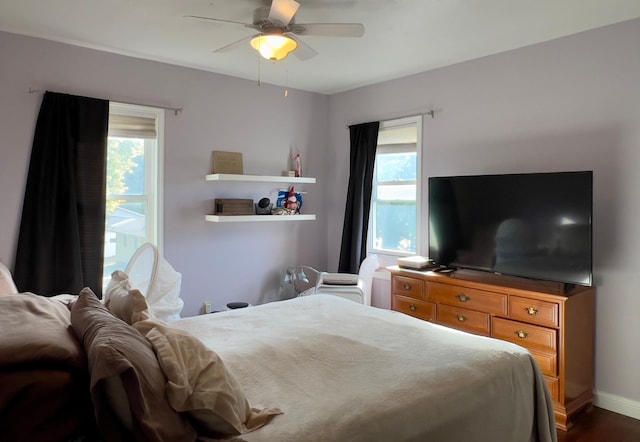 bedroom with multiple windows, a ceiling fan, and baseboards