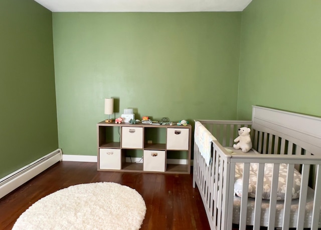 bedroom featuring a crib, a baseboard radiator, baseboards, and dark wood finished floors