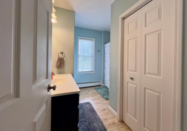 bathroom with a closet, a baseboard heating unit, vanity, wood finished floors, and a shower with curtain