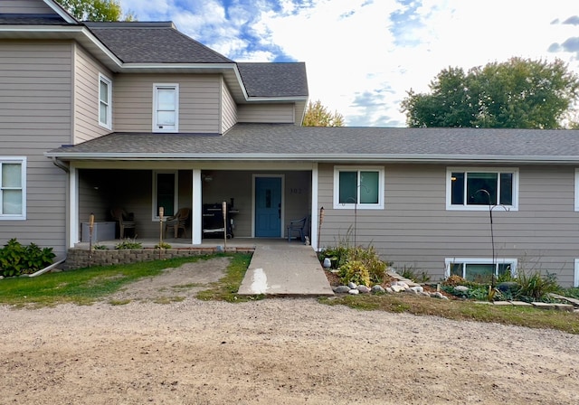 view of front of home with a patio area and roof with shingles