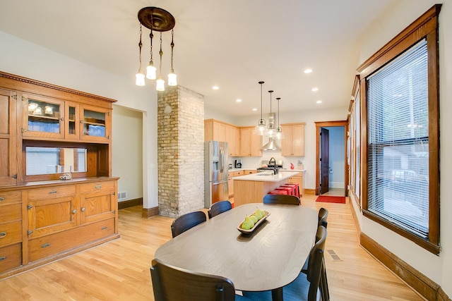 dining room with light wood finished floors, decorative columns, and plenty of natural light