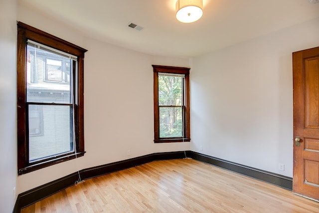 empty room featuring light wood-style flooring, visible vents, and baseboards