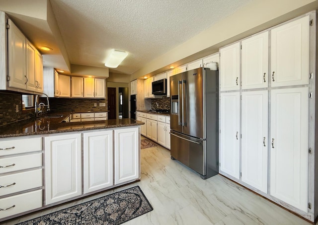 kitchen with dark stone counters, marble finish floor, appliances with stainless steel finishes, and white cabinetry