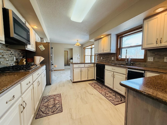 kitchen featuring tasteful backsplash, white cabinets, dark countertops, a peninsula, and stainless steel appliances