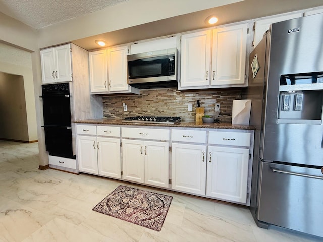 kitchen with white cabinetry, marble finish floor, appliances with stainless steel finishes, tasteful backsplash, and dark countertops